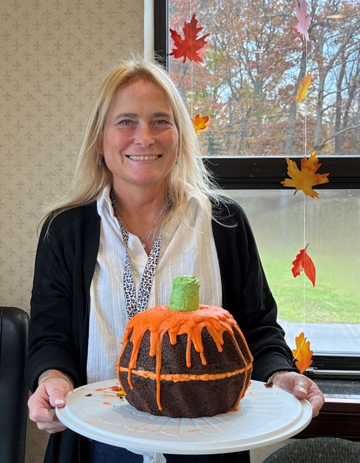 Linda DeNisio holding pumpkin-shaped cake