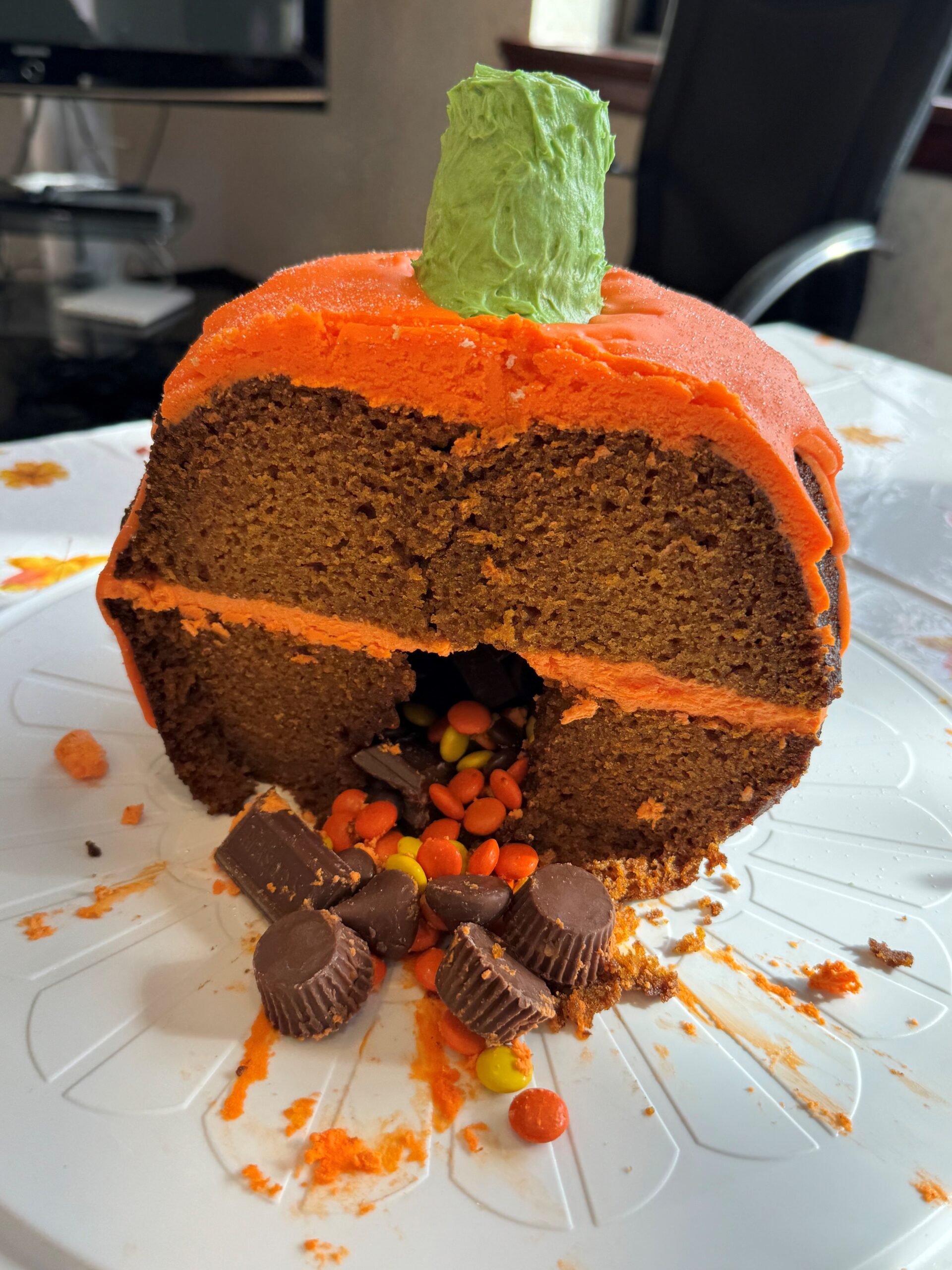 Pumpkin-shaped cake sliced in half with candy filling falling out of center
