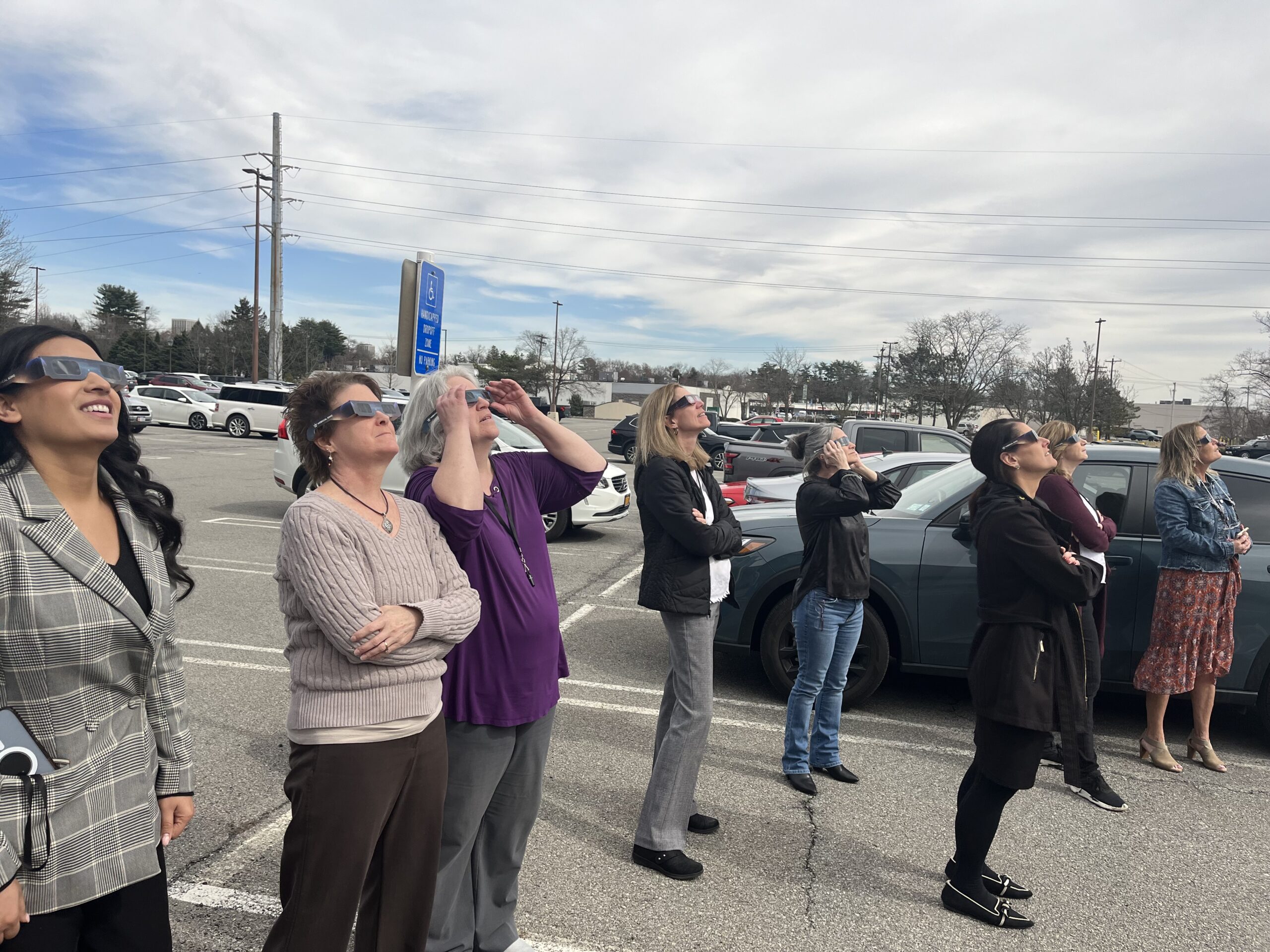 Members of the firm viewing the solar eclipse from the parking lot, wearing solar eclipse viewing glasses.